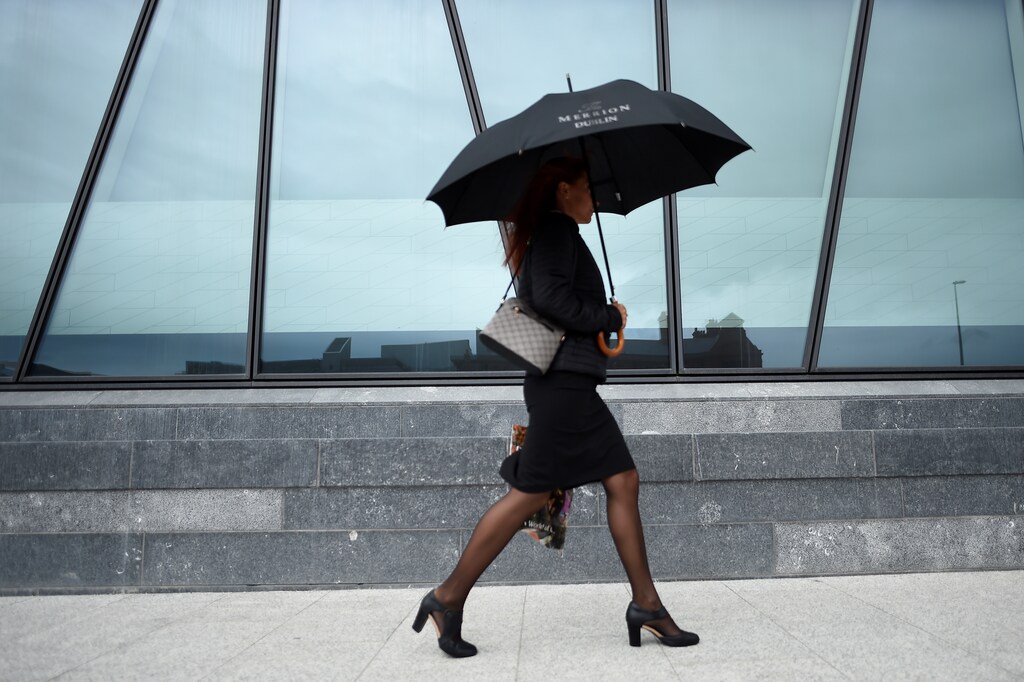 A woman holding an umbrella walks through the financial services area of Dublin, Ireland July 7, 2017. REUTERS/Clodagh Kilcoyne - RTX3AJ8E