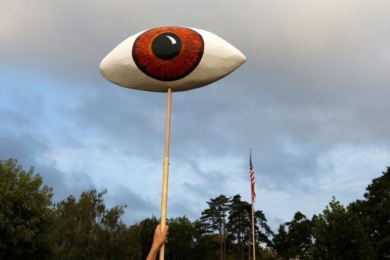 A Greenpeace activist holds a giant eye during a demonstration against the trade agreements TTIP, CETA and TiSA in front of the U.S. Mission in Geneva, Switzerland, September 20, 2016. REUTERS/Denis Balibouse - S1BEUCIPIWAA