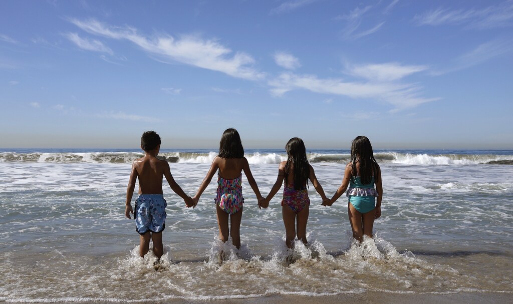 Children walk into the Pacific Ocean in Santa Monica, California October 4, 2014.