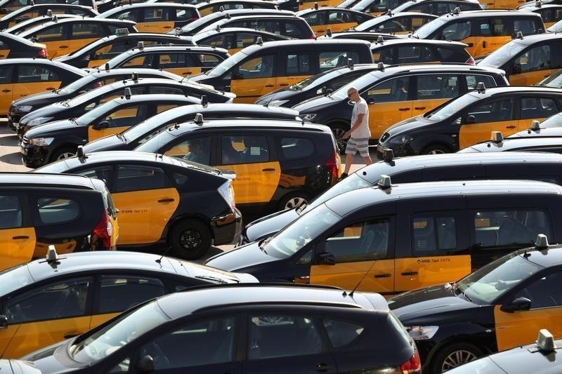 A taxi driver walks through parked taxis at Barcelona-El Prat airport during a strike against what they say is unfair competition from ride-hailing and car-sharing services such as Uber and Cabify in Barcelona, Spain, July 26, 2018.