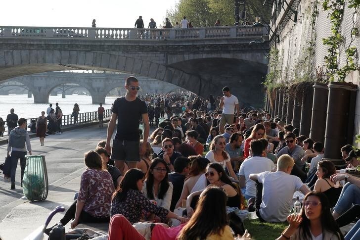 People are seen on the banks of the Seine River during sunny weather in Paris, France April 18, 2018. REUTERS/Gonzalo Fuentes