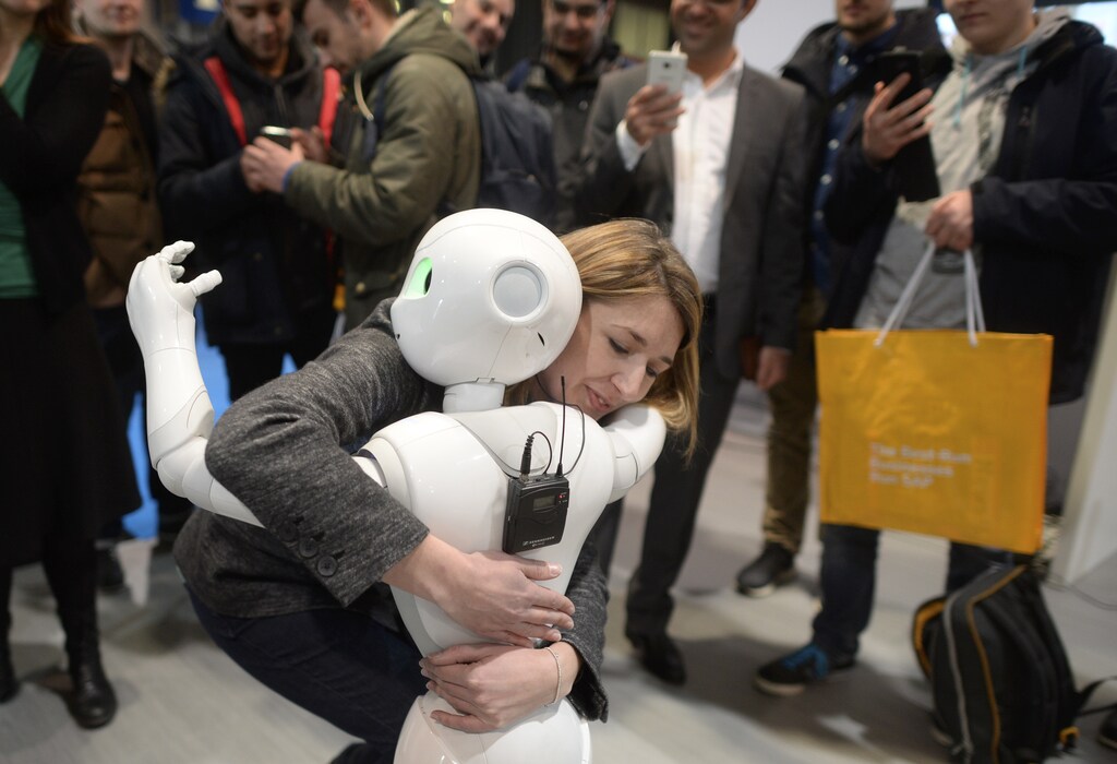 A woman embraces humanoid robot Pepper at the world's biggest computer and software fair CeBit in Hanover, Germany, March 14, 2016. REUTERS/Nigel Treblin - LR1EC3E11MITJ