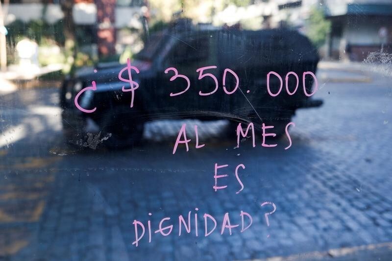 A painted glass reading "350.000 (Chilean peso) a month is dignity?" reflects an armored vehicle during a protest at Providencia, a wealthy neighborhood, in Santiago, Chile November 6, 2019. REUTERS/Jorge Silva REFILE - CORRECTING CURRENCY - RC2X5D9X82GM