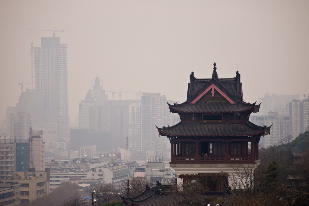 A bold contrast between a Chinese traditional structure and modern buildings in a city filled with exhaust: Air pollution causes significant economic impacts as well as on health.