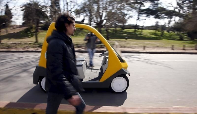 A man walks next to a prototype of an autonomous electric vehicle during its presentation in Buenos Aires, August 19, 2015. The autonomous vehicle, the first of its kind developed in Argentina, is able to fulfill the main functions of mobility of a traditional car but autonomously through the use of artificial intelligence that enables it to detect their surroundings and move without human intervention. REUTERS/Marcos Brindicci - RTX1OUDA