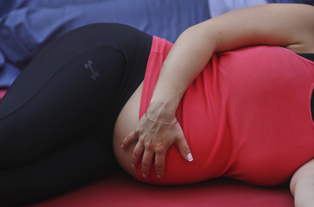 A pregnant woman touches her stomach as people practice yoga on the morning of the summer solstice in New York's Times Square June 20, 2012. The "Solstice in Times Square" event on Wednesday brought out thousands of participants to celebrate the year's longest day in New York.REUTERS/Shannon Stapleton (UNITED STATES - Tags: ANNIVERSARY SOCIETY) - GM1E86K1OO401