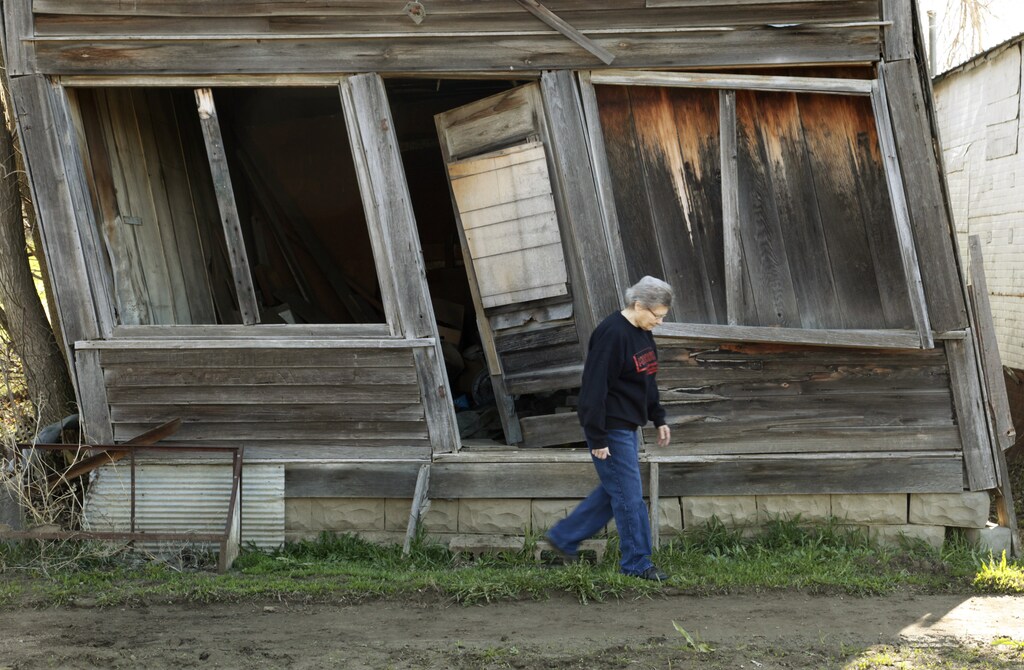Elsie Eiler walks past an abandoned building that was once a general store slowly decaying in Monowi, Nebraska April 28, 2011. At its peak in the 1930's the town had 150 residents but after the railroad left it began to decline. Now down to a population of just one, Monowi is the only incorporated town, village or city in the United States with just a single resident. The general store closed when World War II started and the owner moved out of town to serve on the draft board. REUTERS/Rick Wilking (UNITED STATES) - LM2E7540PWV01