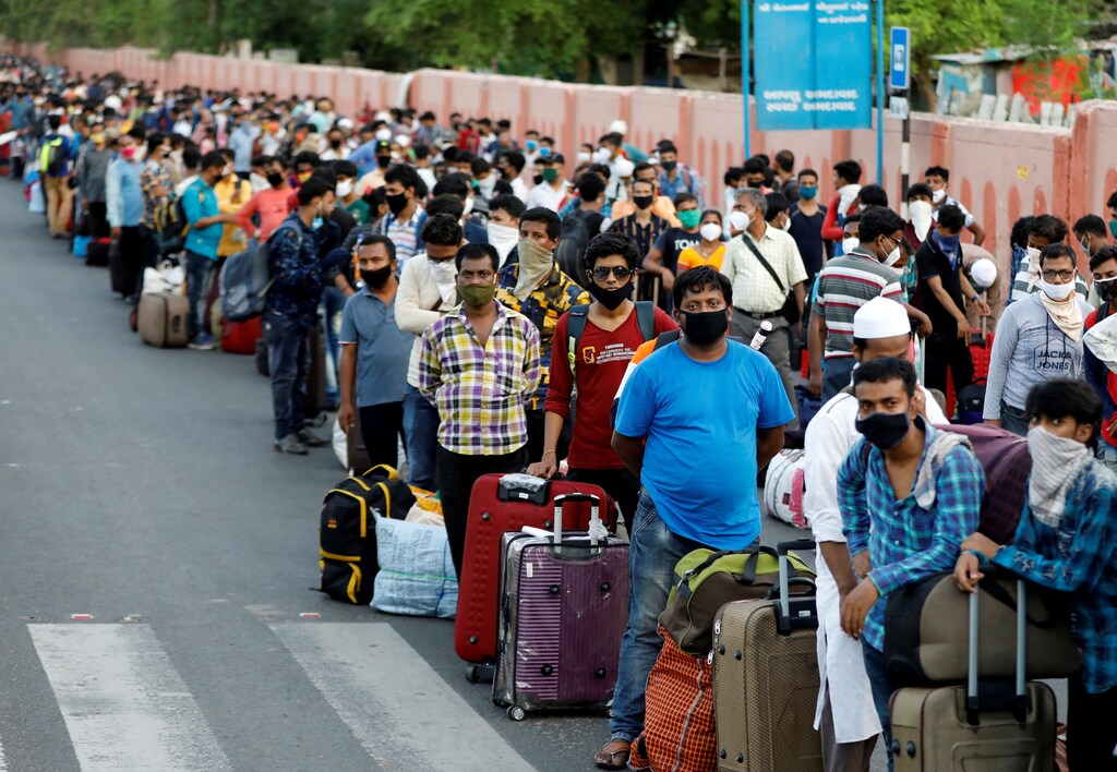Migrant workers and their families wait in lines outside a railway station to board a train to their home state of eastern West Bengal, after authorities eased lockdown restrictions that were imposed to slow the spread of the coronavirus disease (COVID-19), in Ahmedabad, India, June 18, 2020. REUTERS/Amit Dave TPX IMAGES OF THE DAY - RC2RBH9F7GLD