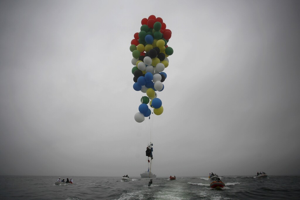 South Africa's Matt Silver-Vallance floats above the sea using helium filled balloons from the airfield of Robben Island across the Atlantic Ocean in Cape Town April 6, 2013. Vallance made the 7 km flight to raise funds and awareness for the Nelson Mandela Children's Hospital. Mandela left hospital on Saturday after more than a week of treatment of pneumonia that raised global concern about the health of the 94-year-old anti-apartheid leader. REUTERS/Mark Wessels (SOUTH AFRICA - Tags: POLITICS SOCIETY TPX IMAGES OF THE DAY) - GM1E9461ULG01