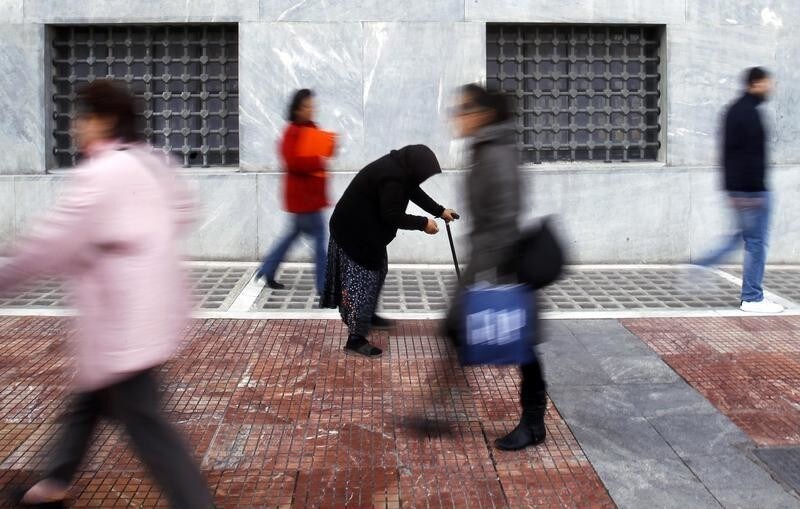 A woman begs as shoppers walk by in central Athens February 21, 2012.Greeks resigned themselves on Tuesday to a 130-billion-euro EU/IMF bailout that won their country a last-minute reprieve from bankruptcy at the price of a decade of austerity and humiliating foreign scrutiny of national finances. REUTERS/Yannis Behrakis (GREECE - Tags: BUSINESS POLITICS) - RTR2Y6YK
