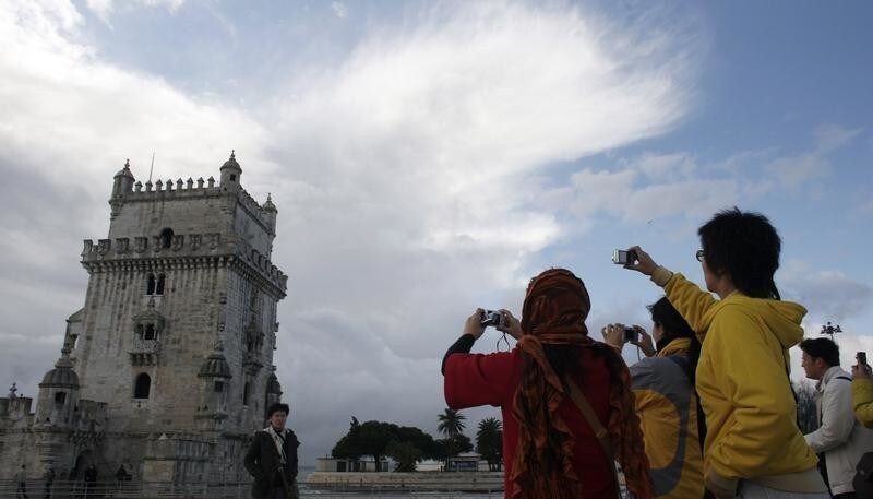 Japanese tourists take pictures in front of Belem Tower in Lisbon November 28, 2008. The global crisis may be pounding bigger travel markets in Europe but it's almost business as usual for Portugal's tourism industry. Cheaper to live in and visit than most of western Europe, the small but diverse Iberian country with sunny beaches, historic sites and some of Europe's finest golf courses has eked out modest growth in tourist numbers so far in 2008, after a record 2007, while others are ebbing. REUTERS/Nacho Doce (PORTUGAL) - GM1E4BT04VX01