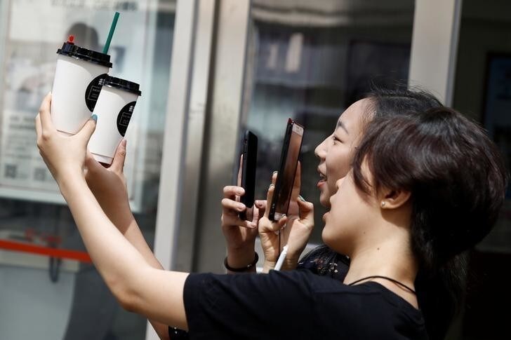 Customers take pictures of cups of tea named in the fashion of the Sang subculture at the Sung Tea shop in Beijing, August 24, 2017. The tea creations are called: "You are the Fattest" and "You don't have nothing, you have a disease". Picture taken August 24, 2017. REUTERS/Thomas Peter