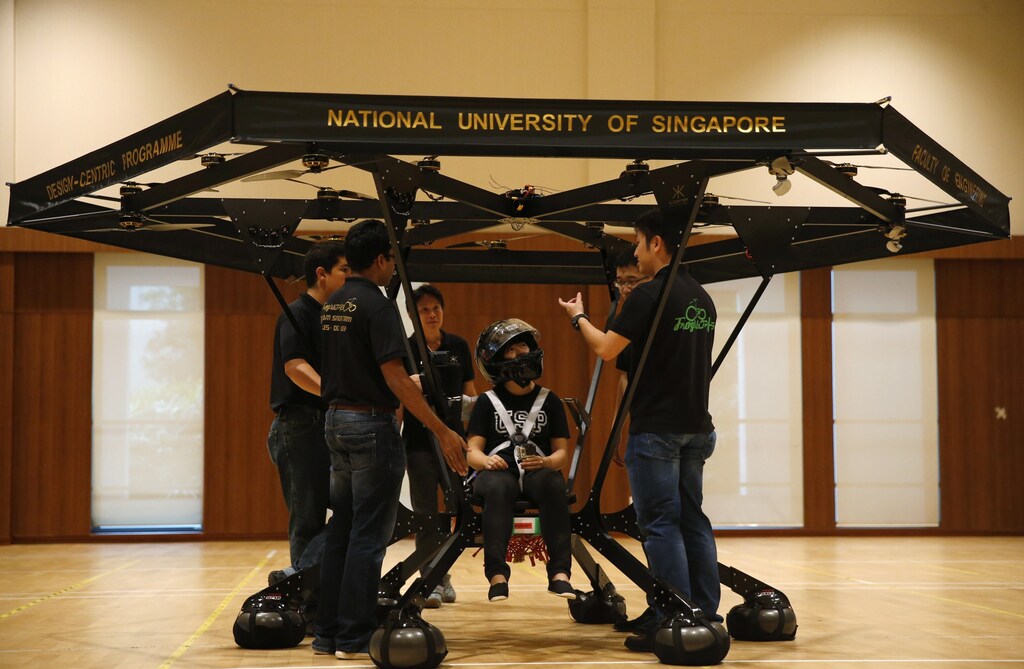 Zheng Xiaowen sits in the Snowstorm, a personal flying machine built by a group of engineering students of the National University of Singapore (NUS), as team members discuss in NUS gymnasium in Singapore December 10, 2015.