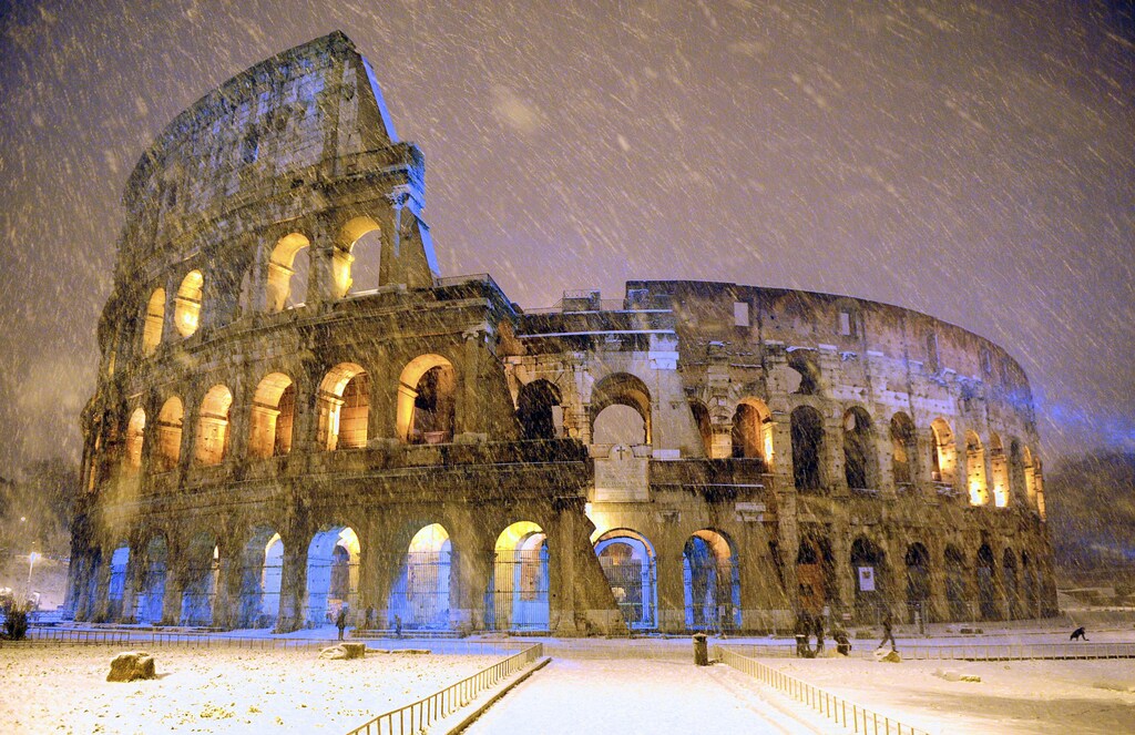 The ancient Colosseum is seen during an heavy snowfalls late in the night in Rome