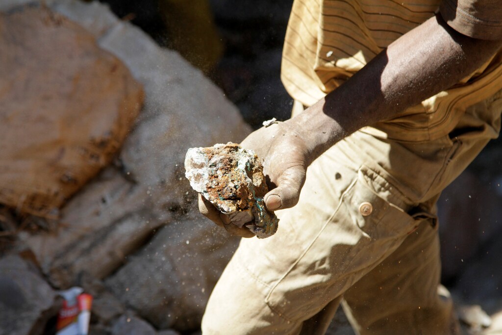 An miner carries raw ore at a former industrial copper-cobalt mine in the Democratic Republic of the Congo