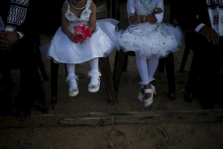 Girls accompany grooms as they sit separate from the brides during a mass wedding for 150 couples in Beit Lahiya town in the northern Gaza Strip July 20, 2015. The wedding was funded by al-Basheer Society for Relief and Development. REUTERS/Suhaib Salem