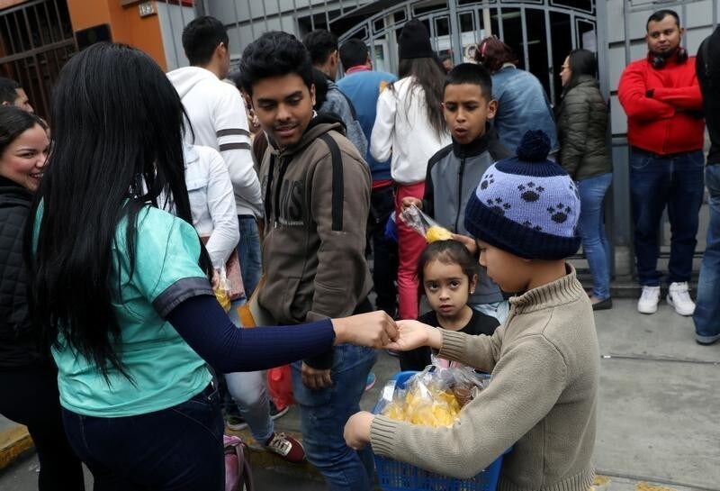 A Venezuelan migrant child sells food outside their embassy while others wait to register for a flight to return to their country, in Lima, Peru September 5, 2018.