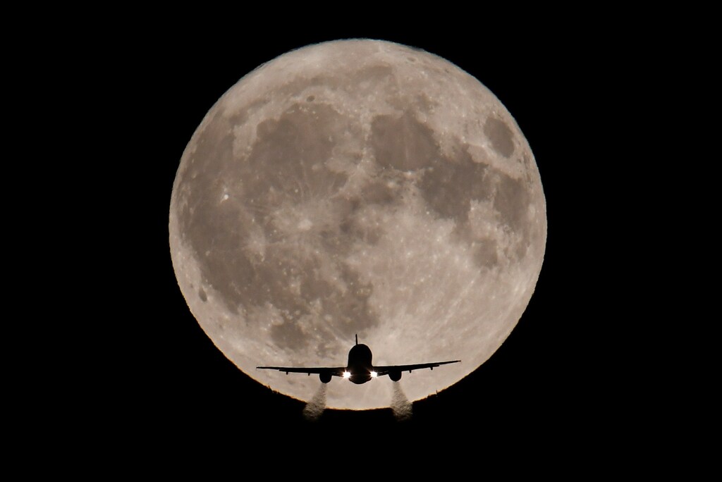 A passenger plane, with a full Harvest moon seen behind, makes its final landing approach towards Heathrow Airport in London, Britain, October 5, 2017. REUTERS/Toby Melville - RC1CFE1838B0