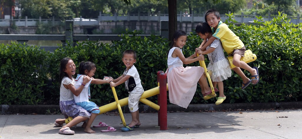 Yang Hongnian and Le Huimin's six children play on a see-saw outside their home in Jinhua, Zhejiang province, August 7, 2014