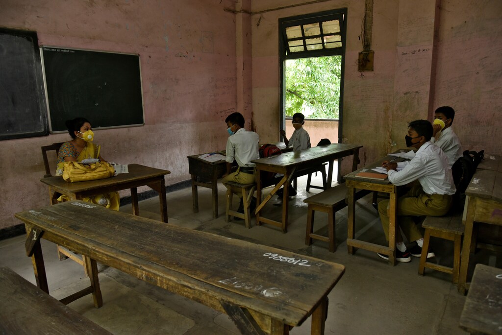 Students and their teacher wear protective face masks inside a classroom to stop the spread of covid-19