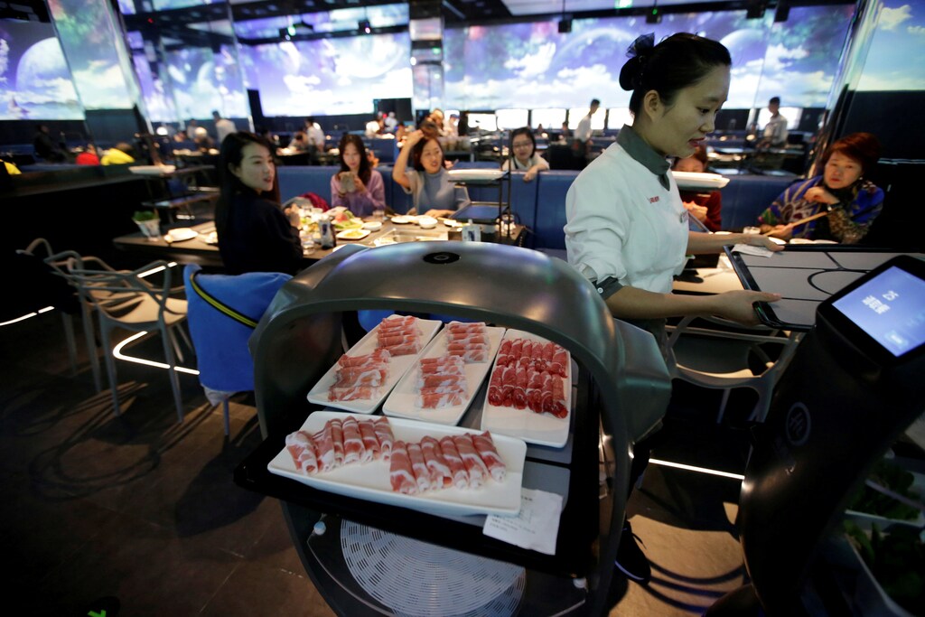 A robot waiter arrives at a table in a Beijing restaurant.