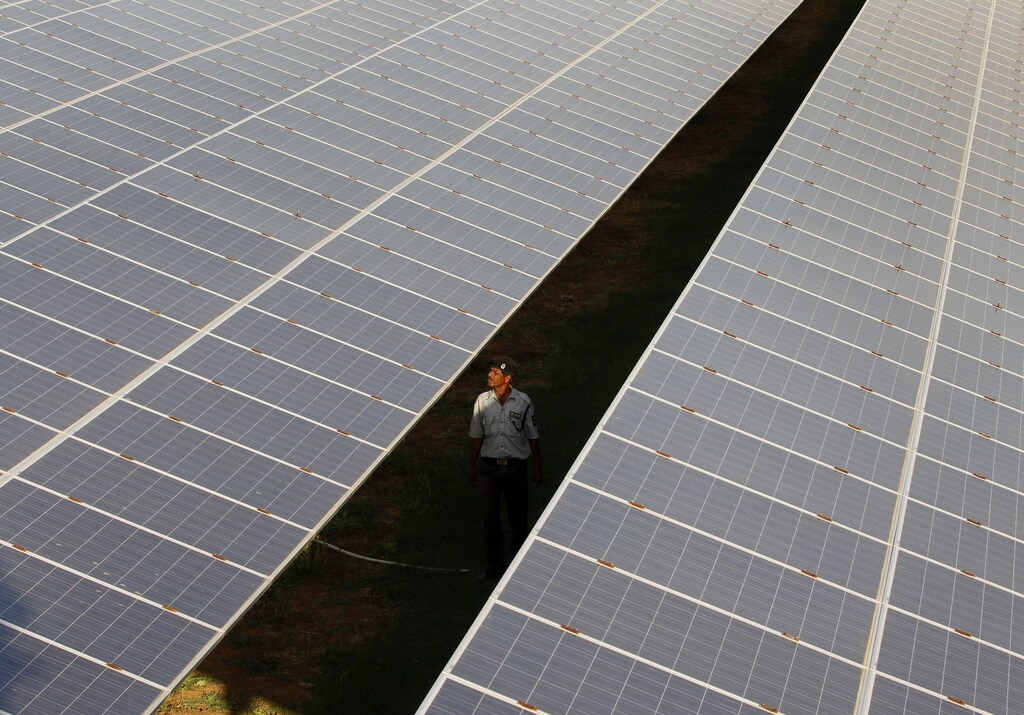 A private security guard walks between rows of photovoltaic solar panels inside a solar power plant at Raisan village near Gandhinagar, in the western Indian state of Gujarat, February 11, 2014. India said on Tuesday it was investigating U.S. policies supporting solar panel makers, the latest move in an escalating row over renewable energy that has worsened already strained ties between the two countries. REUTERS/Amit Dave (INDIA - Tags: POLITICS BUSINESS ENERGY TPX IMAGES OF THE DAY) - GM1EA2B1RUN01