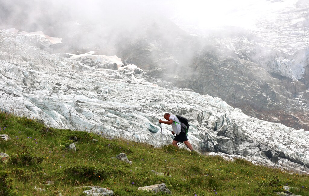 A hiker walks past the Bionnassay glacier, the smallest glacier of the Mont Blanc complex in France, which is shrinking under the the influence of global warming, according to many scientists, August 18, 2021. REUTERS/Yann Tessier - RC2O7P9CNO0Q