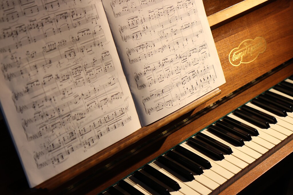 Music score resting on a brown piano.