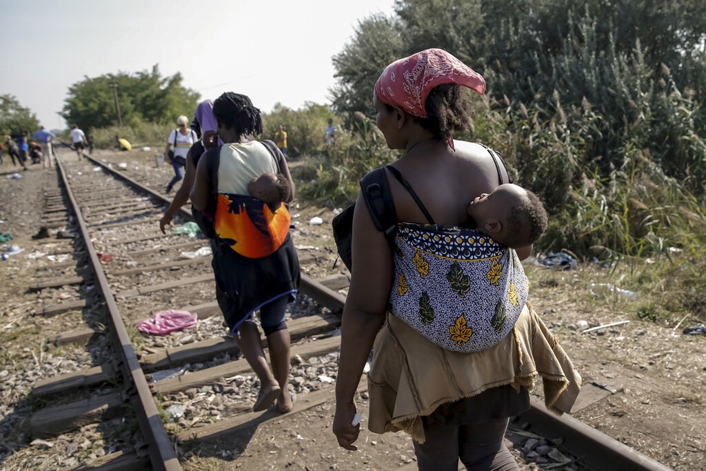 Migrants, hoping to cross into Hungary, walk with babies on their backs along a railway track outside the village of Horgos in Serbia, towards the border it shares with Hungary August 31, 2015. REUTERS/Marko Djurica - GF10000188067