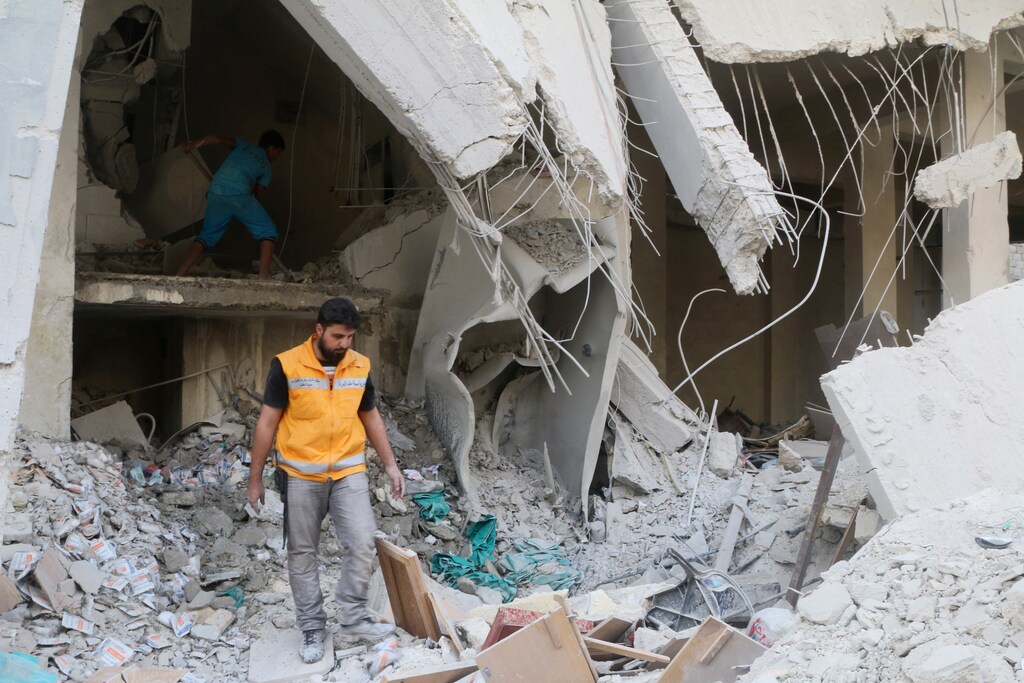 A Red Crescent aid worker inspects scattered medical supplies after an airstrike on a medical depot in the rebel-held Tariq al-Bab neighbourhood of Aleppo, Syria April 30, 2016.