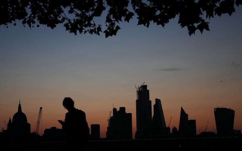 A man walks past the city of London financial district as dawn breaks in London, Britain August 20, 2019. REUTERS/Hannah McKay - RC18BB49F780
