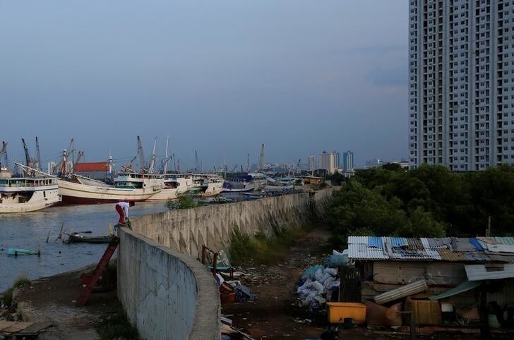 A child stands on a concrete sea wall near the port of Sunda Kelapa in Jakarta, Indonesia, April 6, 2018. REUTERS/Beawiharta