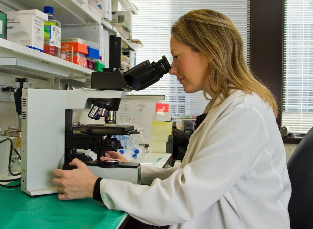 Female scientist looking into a microscope.