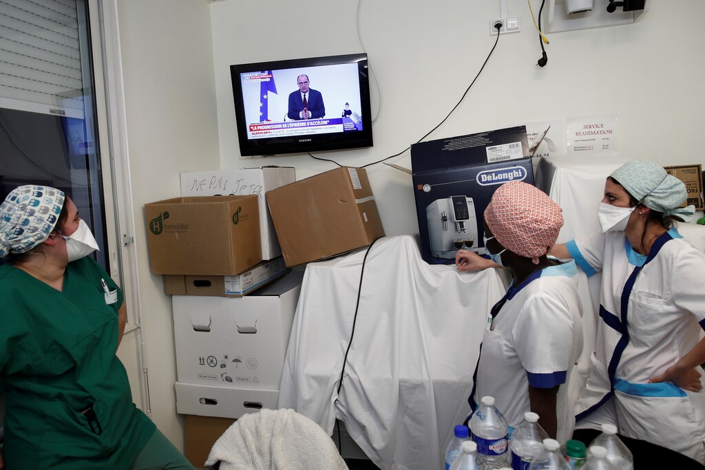 Medical staff members watch French Prime Minister Jean Castex on TV as he addresses the nation about the coronavirus disease (COVID-19) outbreak and the lockdown restrictions at the Clinique de l'Estree - ELSAN private hospital in Stains, near Paris, France, March 18, 2021. REUTERS/Benoit Tessier - RC2UDM9GLJUG