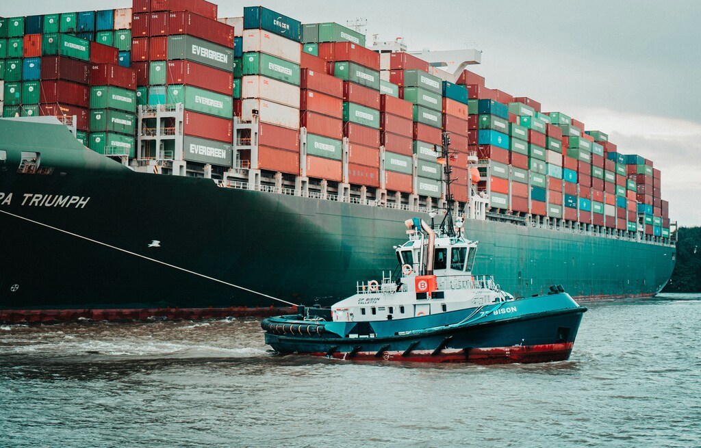 A container ship being tugged into port, illustrating supply chains