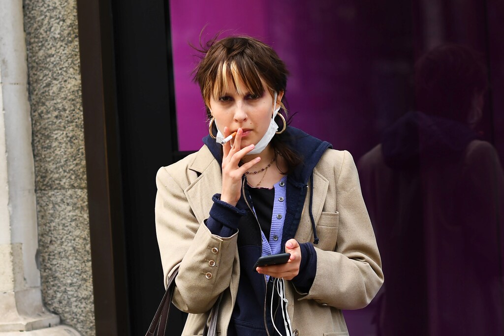A woman smokes a cigarette while wearing a mask, as the number of coronavirus cases grow around the world, in central London, Britain March 14, 2020.