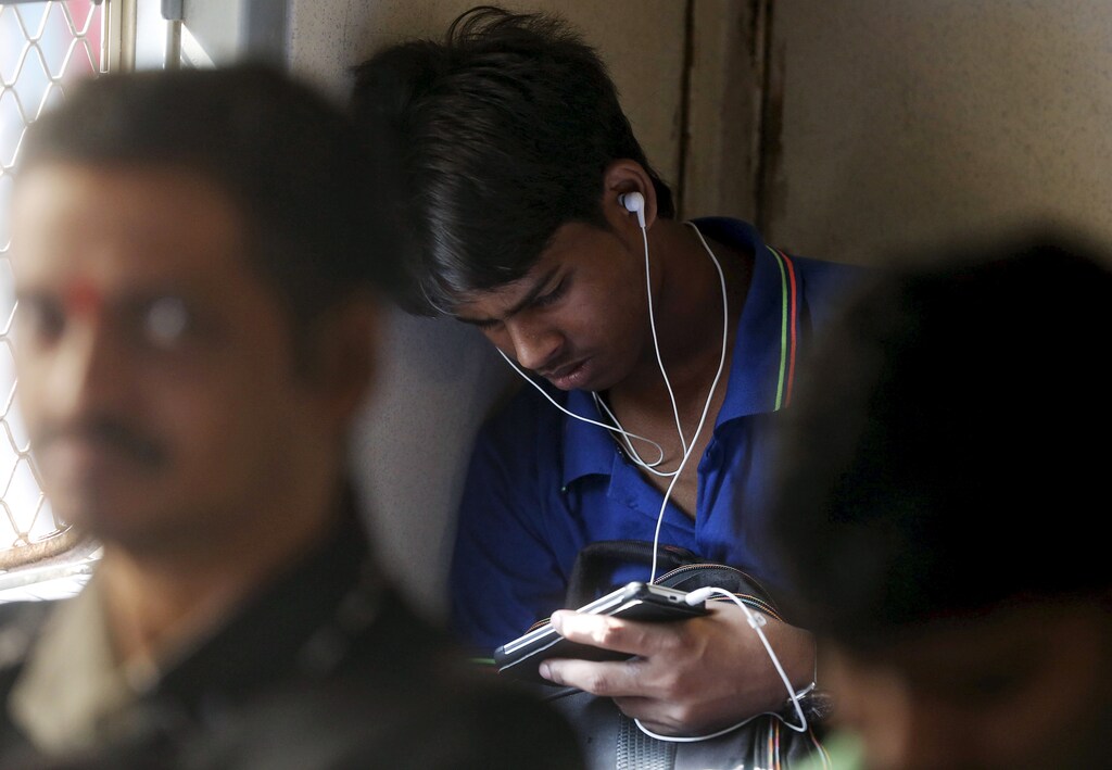 A man watches a video on his mobile phone as he commutes by a suburban train in Mumbai, India, March 31, 2016. With smartphone sales booming and India preparing for nationwide 4G Internet access, India's film and TV industry hopes the ease of tapping your phone for the latest release will generate profits at last, overcoming the problems of woefully few cinemas and rampant piracy. Picture taken March 31, 2016. REUTERS/Shailesh Andrade - RTSDS08