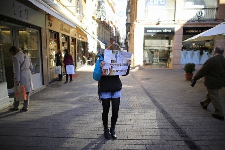 A woman covers her face with a city map in reaction to the photographer, in the central Andalusian capital of Seville January 3, 2013. REUTERS/Marcelo del Pozo (SPAIN - Tags: SOCIETY TRAVEL)