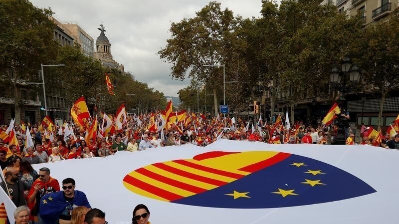 People walk as they hold a Spanish, European and Catalan flag during Spain's National Day in Barcelona, Spain, October 12, 2017. REUTERS/Gonzalo Fuentes - RC1F6D693240