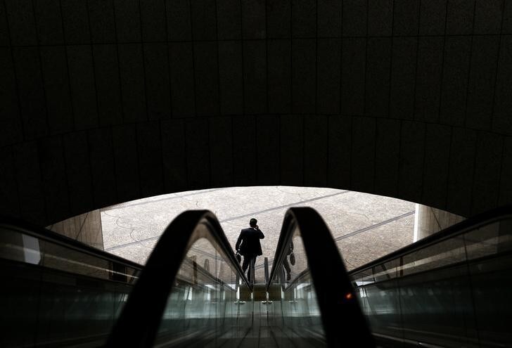 An office worker uses his mobile phone as he leaves an office building in central Sydney July 30, 2013. Consumer prices data out last week showed underlying inflation ran around 2.4 percent in the second quarter, well within the RBA's long-term target band of 2 to 3 percent. Subdued domestic demand, a slowly rising unemployment rate and a benign inflation background all underline the case for further stimulus. REUTERS/Daniel Munoz (AUSTRALIA - Tags: BUSINESS EMPLOYMENT)