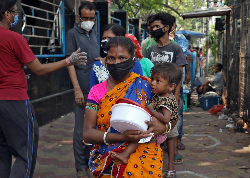 A homeless woman holding a child waits to receive food during a 21-day nationwide lockdown to slow the spreading of the coronavirus disease (COVID-19) in Kolkata, India, April 3, 2020. REUTERS/Rupak De Chowdhuri - RC2YWF9E1LI6
