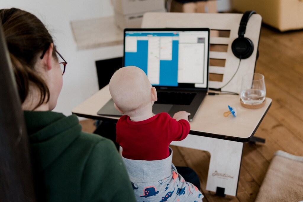 Global Gender gap 2021: working mother at her computer with her baby highlighting how the burden of childcare is falling to women especially during the pandemic