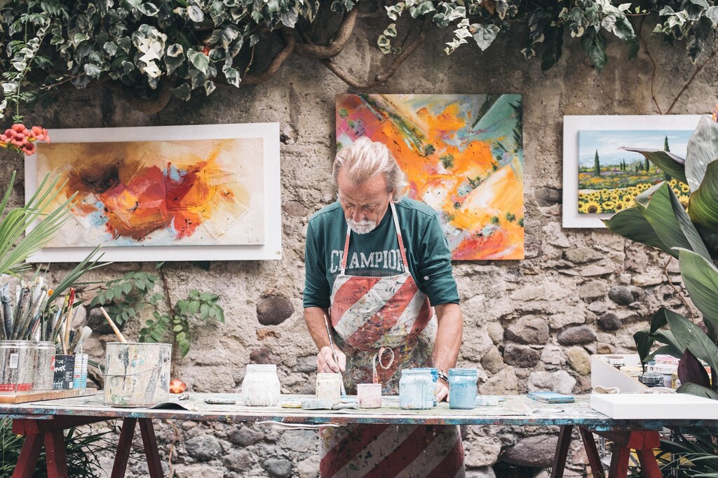 Creative industries: Man in apron, painting on a table.