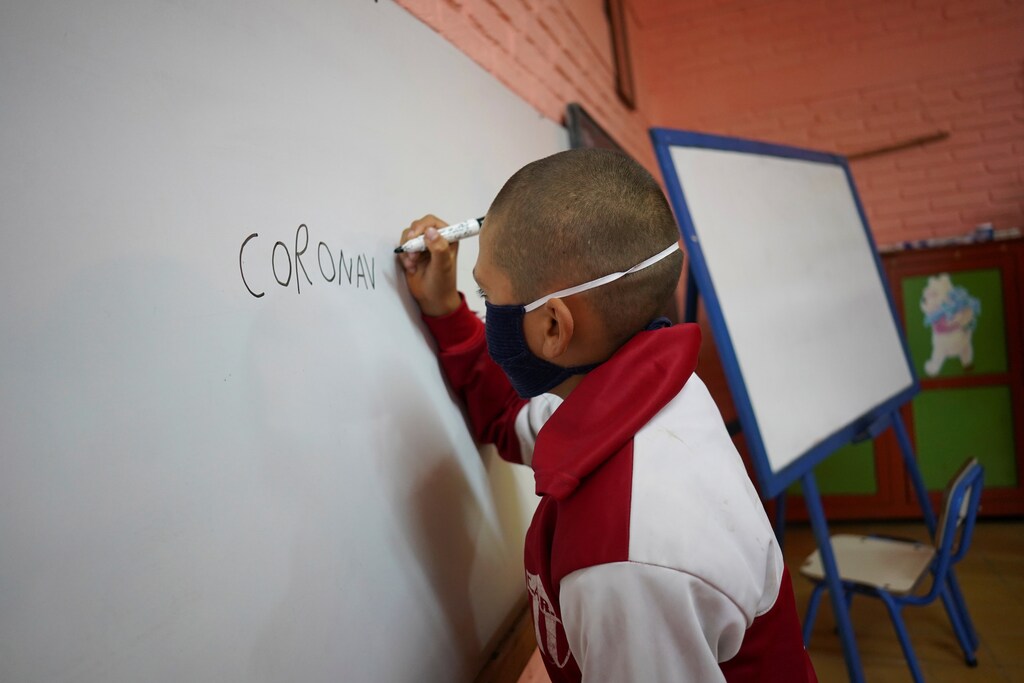 Student Juan Camacho writes the word "coronavirus" on a whiteboard during a lesson at Escuela 30, a rural school that has resumed classes after a month off due to the coronavirus disease (COVID-19), in San Jose, Uruguay April 22, 2020. REUTERS/Mariana Greif - RC21AG9KYTQ0