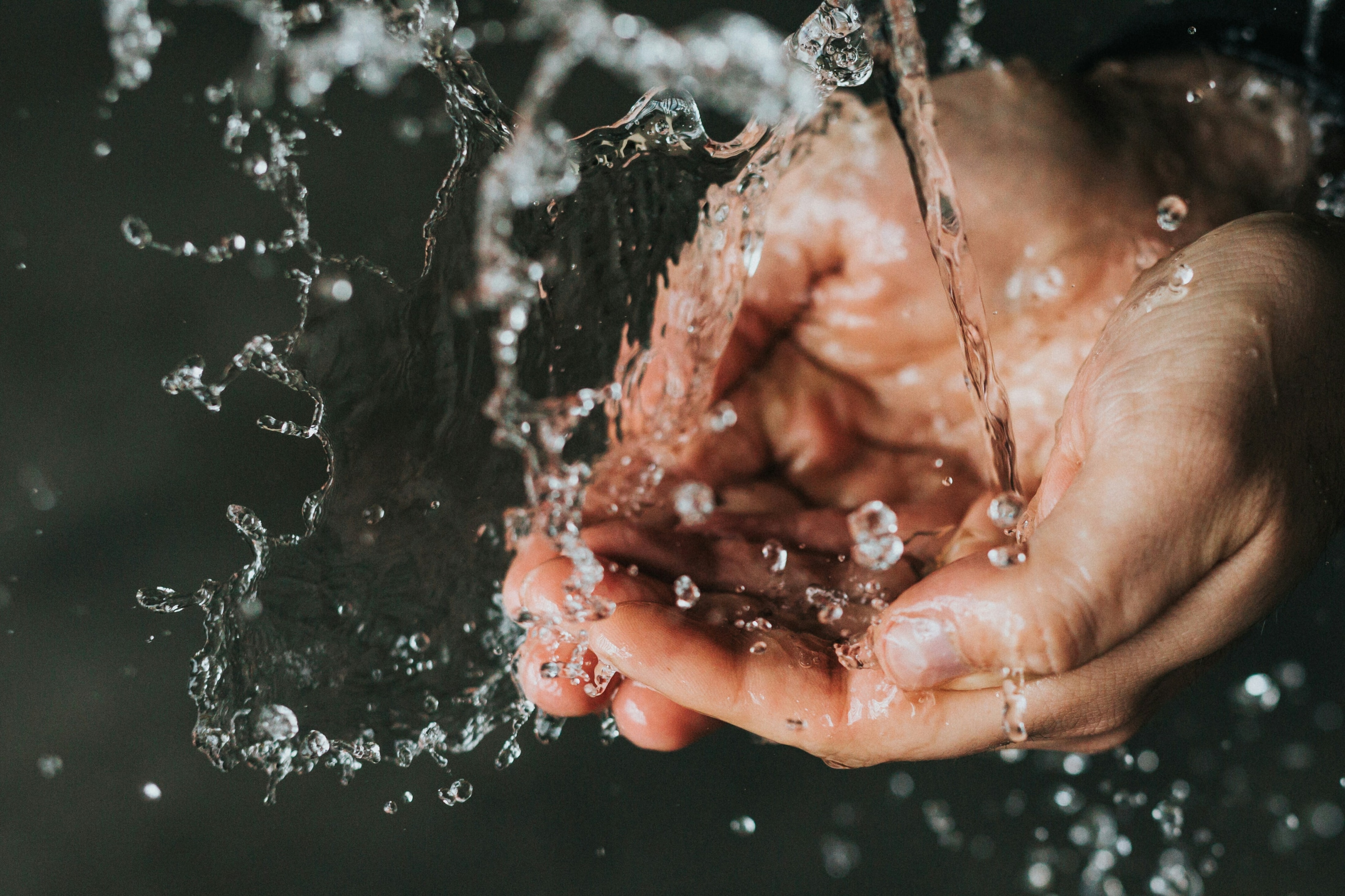 Cupped hands catching water. 