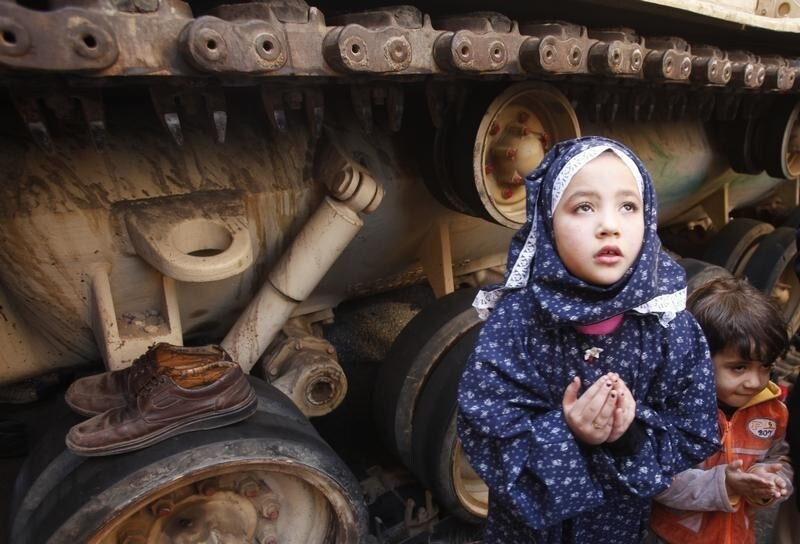 A girl attends Friday prayers in front of an army tank in Tahrir Square in Cairo February 18, 2011. Egyptians held a nationwide "Victory March" on Friday to celebrate the overthrow of Hosni Mubarak's 30-year rule one week ago, to protect the revolution and to remind new military rulers of the power of the street. Hundreds of thousands joined the rallies, which are also a memorial to the 365 people who died in the 18-day uprising, with many Egyptians expressing their intention to guard their newly-won prospect of democracy.