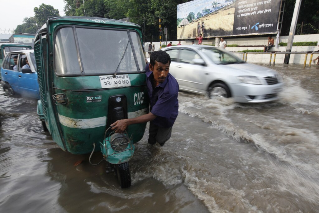 A driver pulls his broken down vehicle in knee deep water caused by heavy rainfall in Dhaka, 2010.