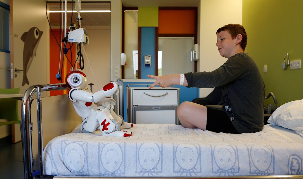 Belgian Ian Frejean, 11, plays with "Zora" the robot, a humanoid robot designed to entertain patients and to support care providers, at AZ Damiaan hospital in Ostend, Belgium June 16, 2016.