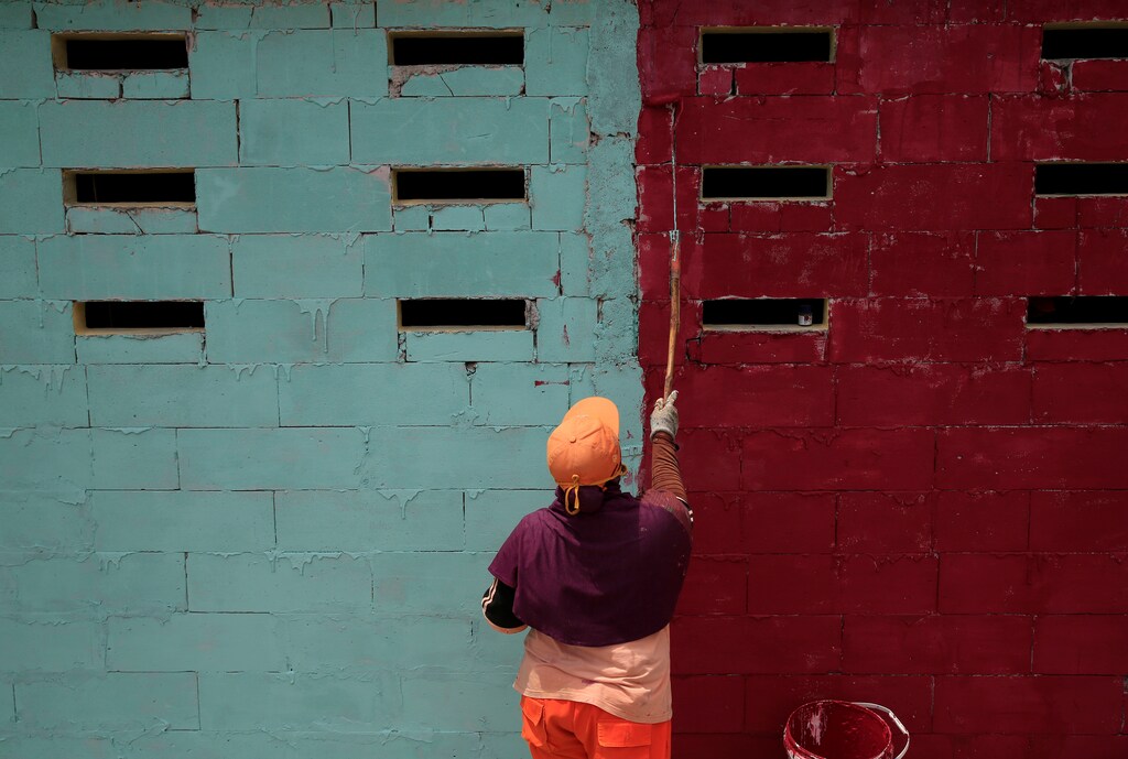 A government worker paints a house wall as part of a clean up campaign ahead of this year's Asian Games in Sunter Jaya, Jakarta, Indonesia, March 22, 2018. REUTERS/Beawiharta - RC1BC8F46EF0