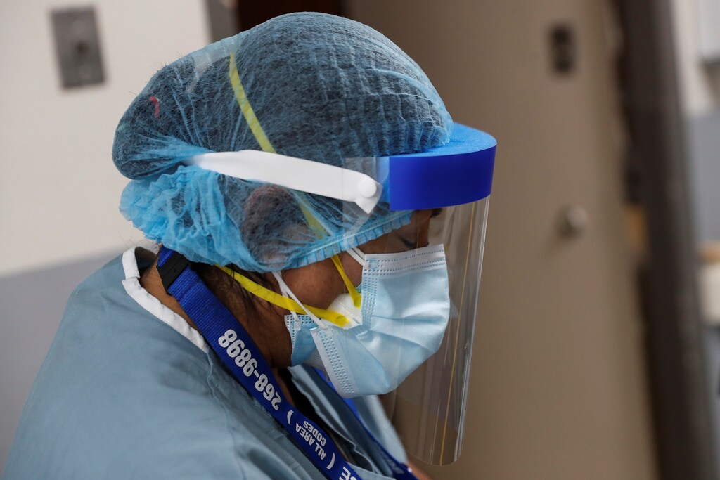 Evelia De La Cruz, a hospital housekeeper at Roseland Community Hospital, looks down while wearing a PPE suit to protect against the coronavirus disease (COVID-19), before cleaning on the South Side of Chicago, Illinois, U.S., December 8, 2020. Picture taken December 8, 2020. REUTERS/Shannon Stapleton - RC2ZKK9NW7Z2